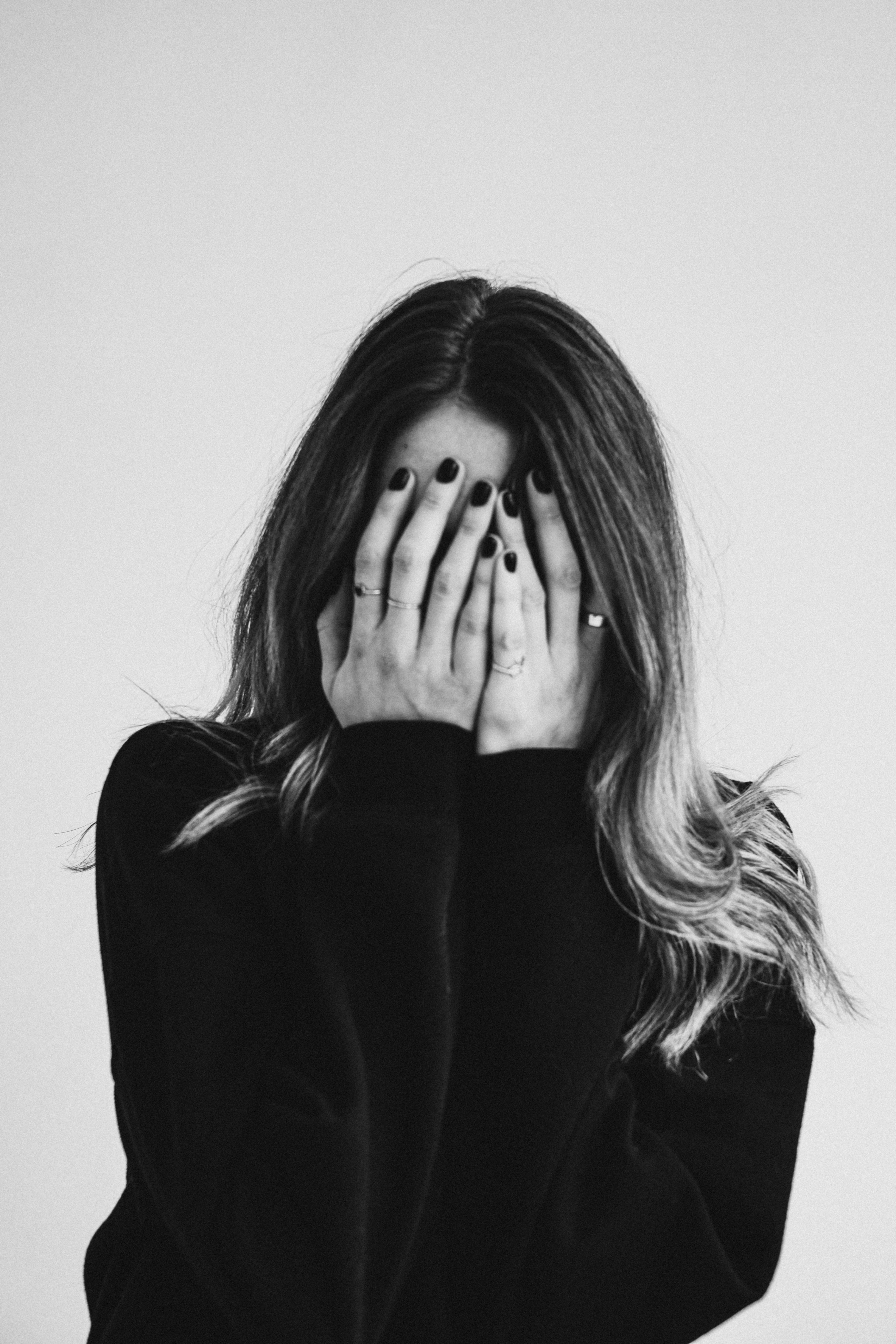 grayscale-photo-of-a-woman-covering-her-face